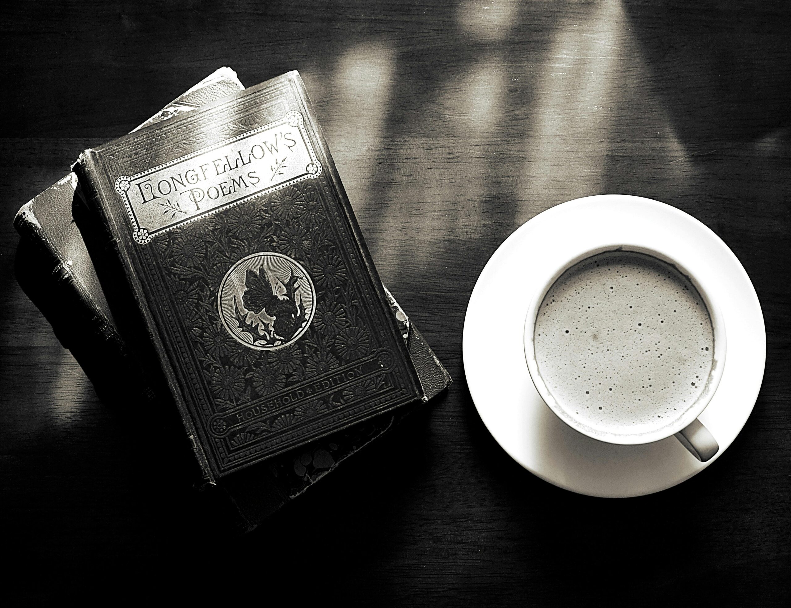 Book of poetry beside a cup of hot coffee or tea on a table