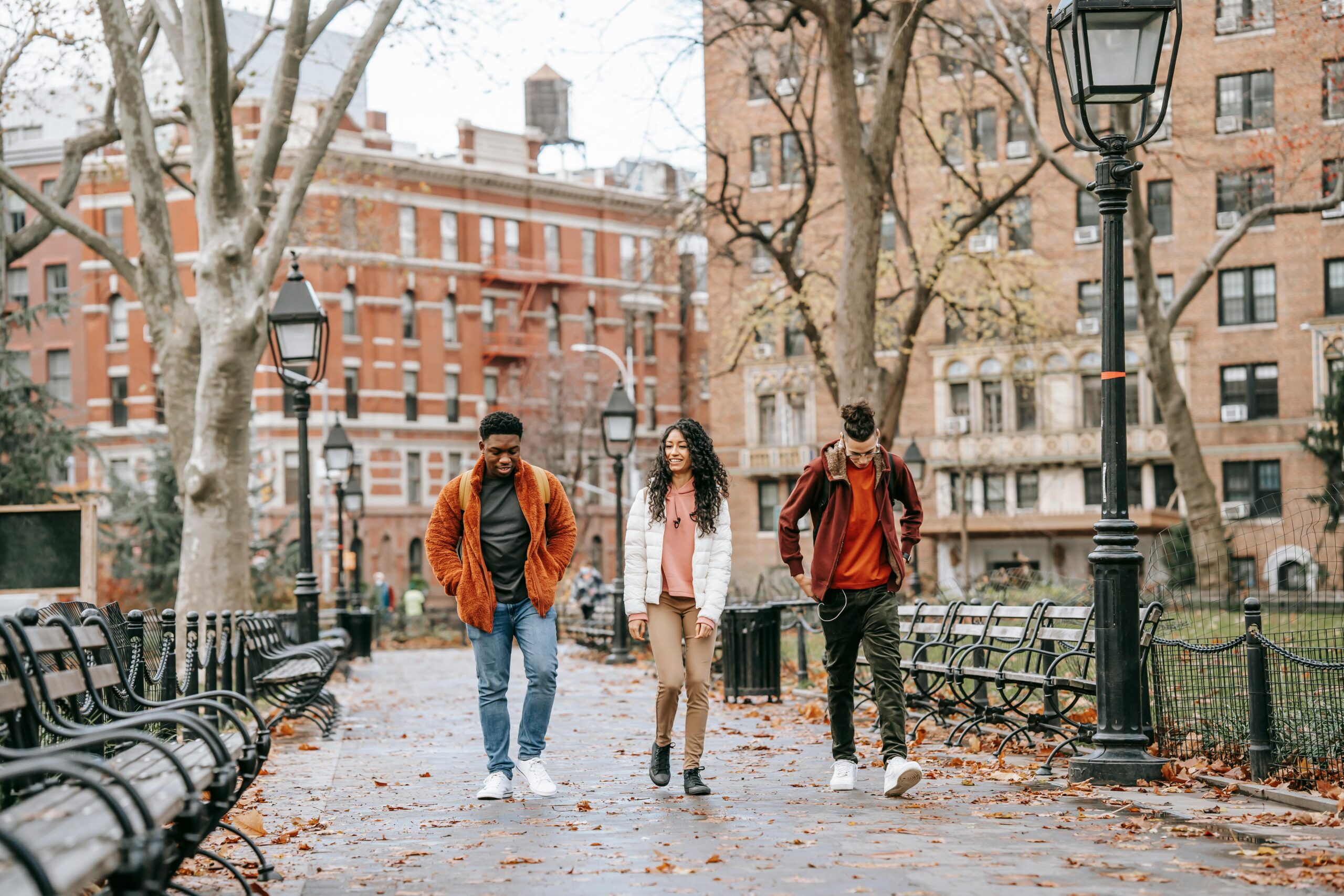 Three teens walking through a park chatting.